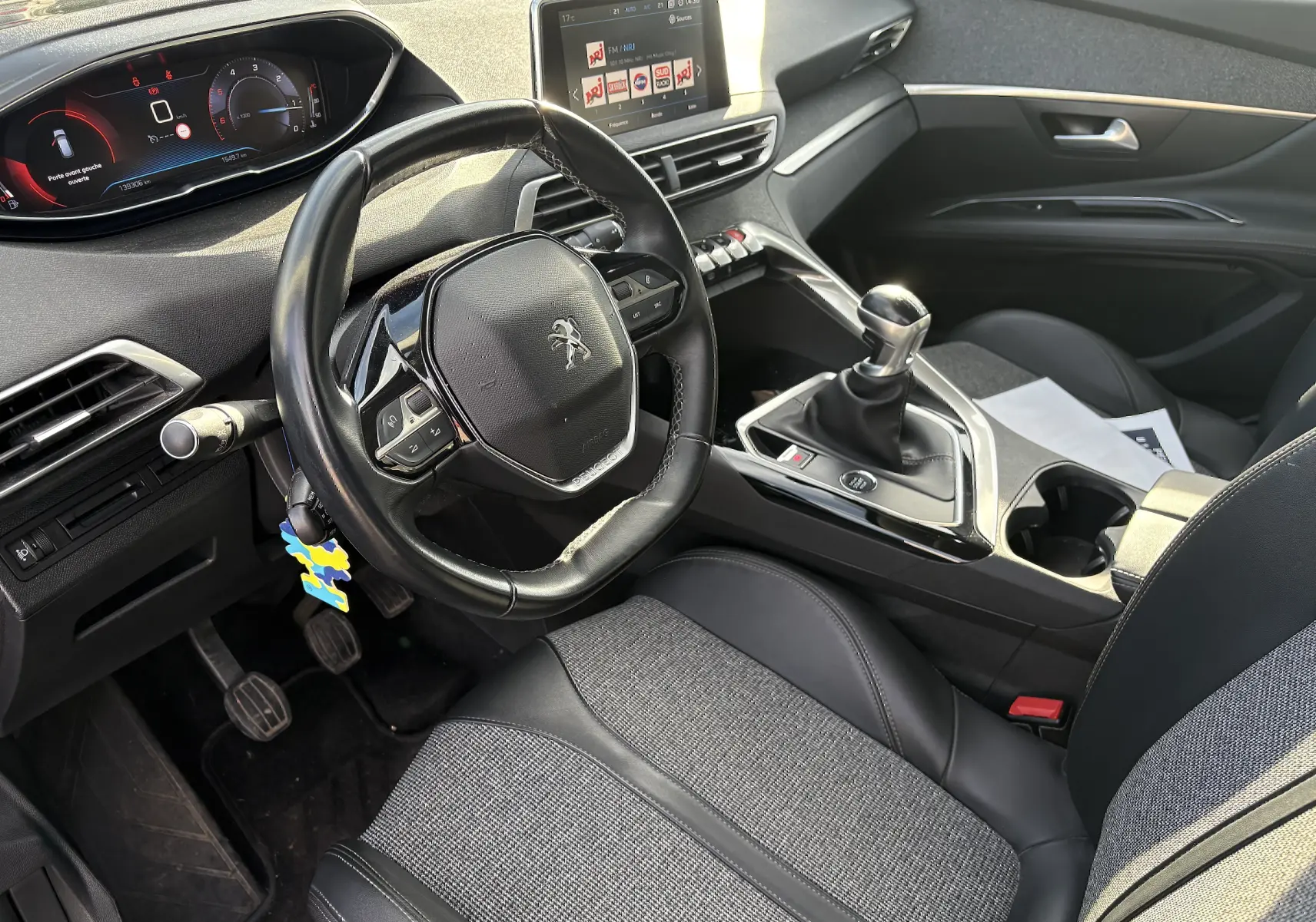 Vue intérieure côté conducteur du Peugeot 3008 II 2019, volant cuir, tableau de bord numérique et levier de vitesse manuel.