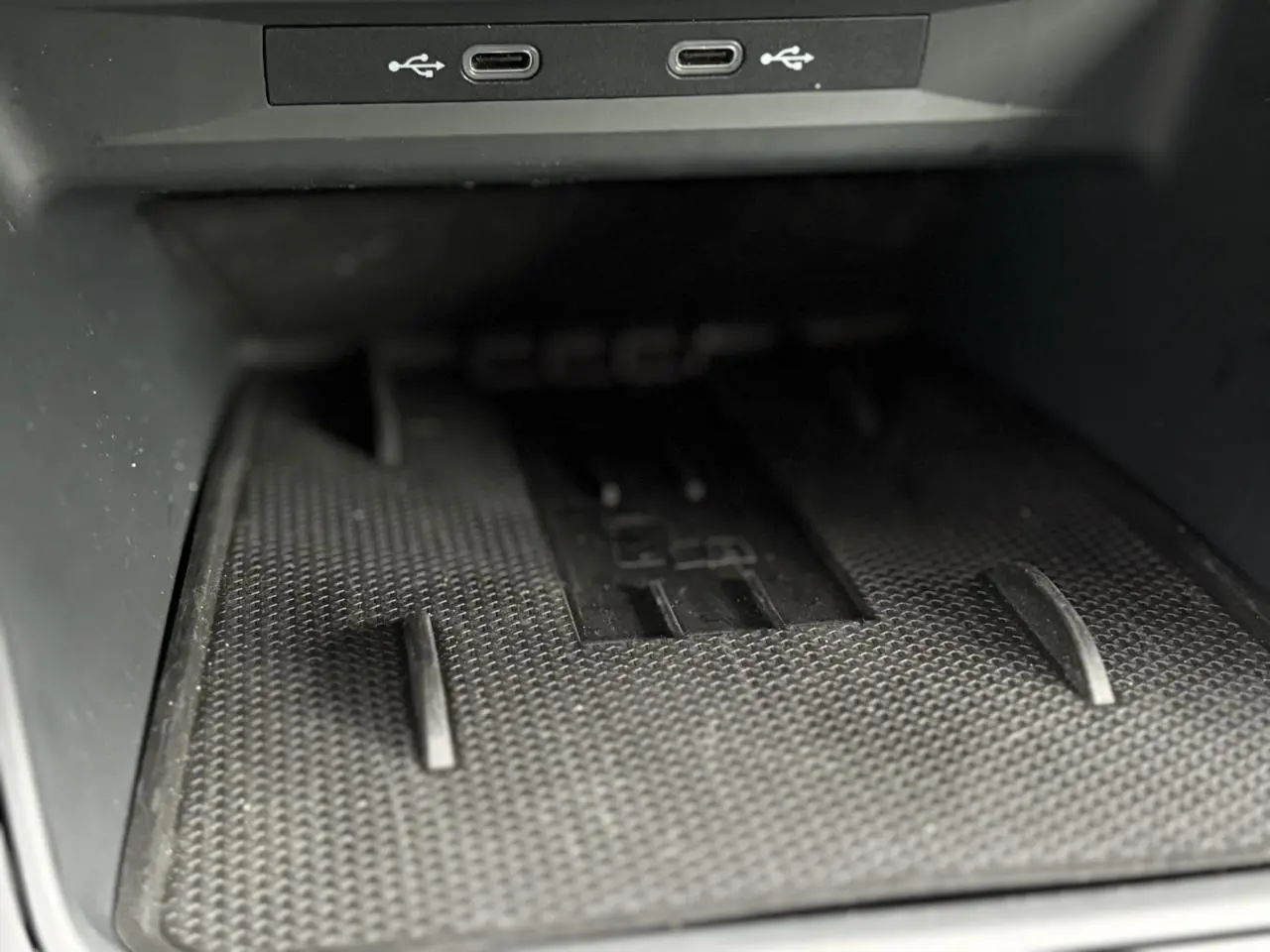 Gros plan sur le chargeur à induction noir avec deux ports USB-C dans la console centrale du CUPRA LEON ST Gris Taiga.