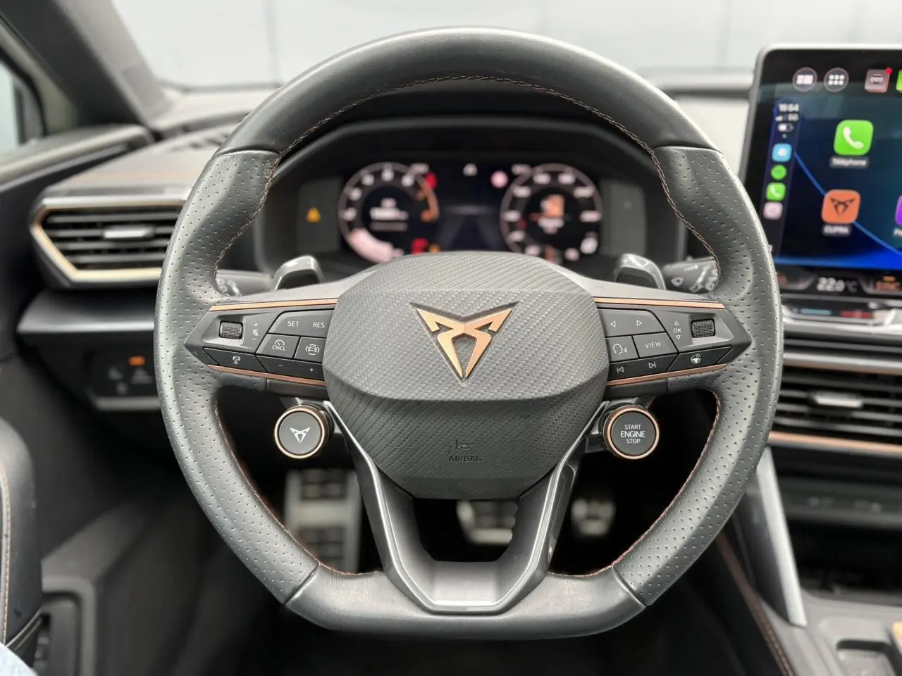 Vue rapprochée du volant cuir perforé noir avec logo CUPRA cuivré et commandes intégrées du CUPRA LEON ST 2025.