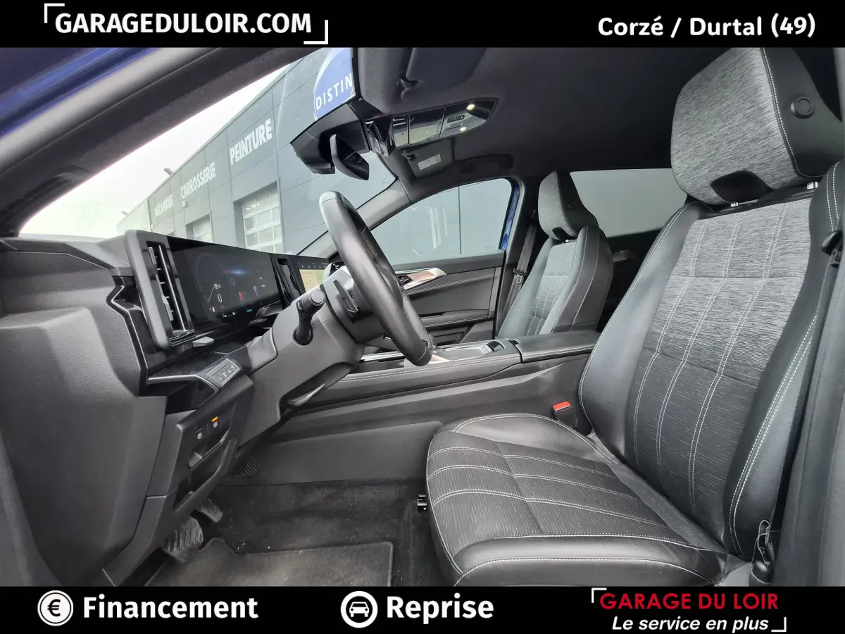 Vue intérieure côté conducteur du Renault Austral 2023 avec sièges tissu et cuir gris, volant multifonctions et tableau de bord numérique.