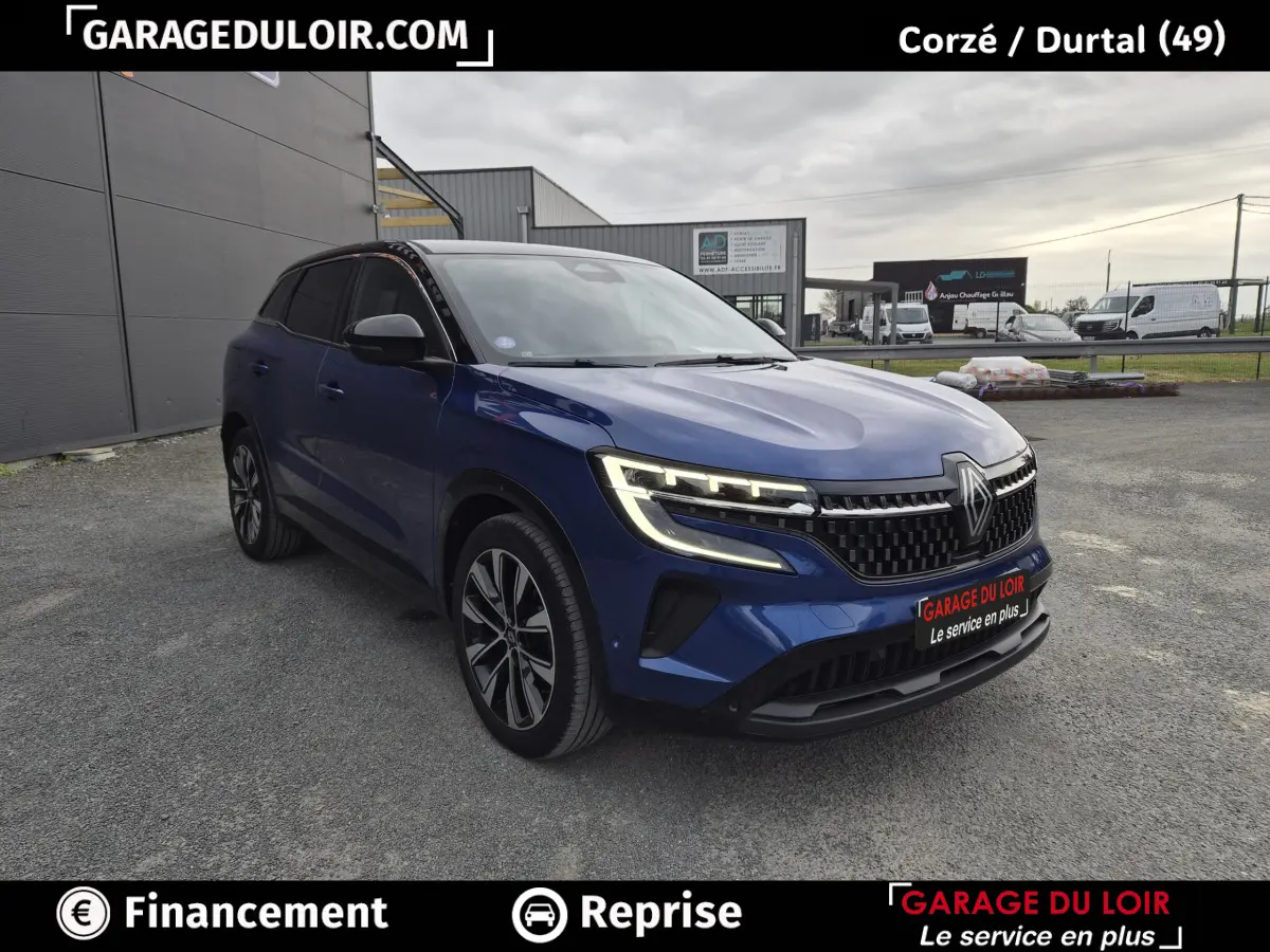 Renault Austral bleu 3/4 avant droit avec calandre noire et phares LED allumés sur parking extérieur.