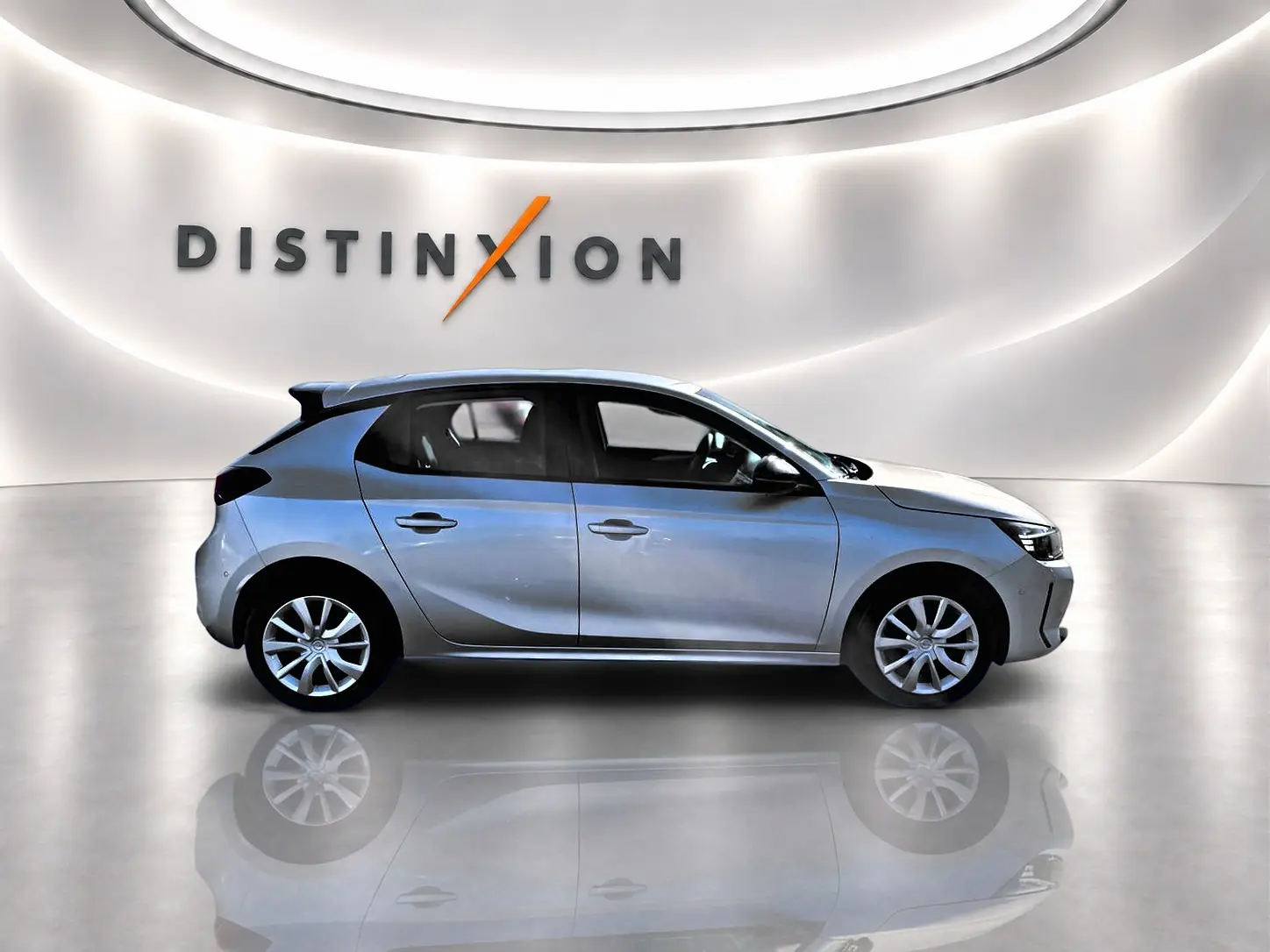 Opel Corsa 2025 gris en profil droit dans un showroom avec logo Distinxion en arrière-plan.