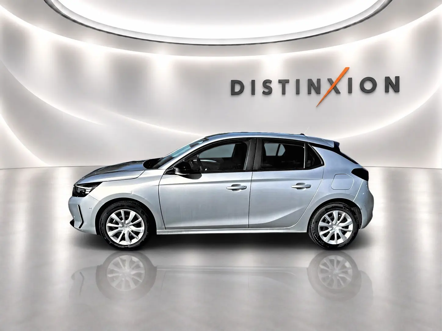 Vue de profil côté gauche d'une Opel Corsa gris métallisé 2025 dans un studio lumineux avec logo Distinxion en arrière-plan.