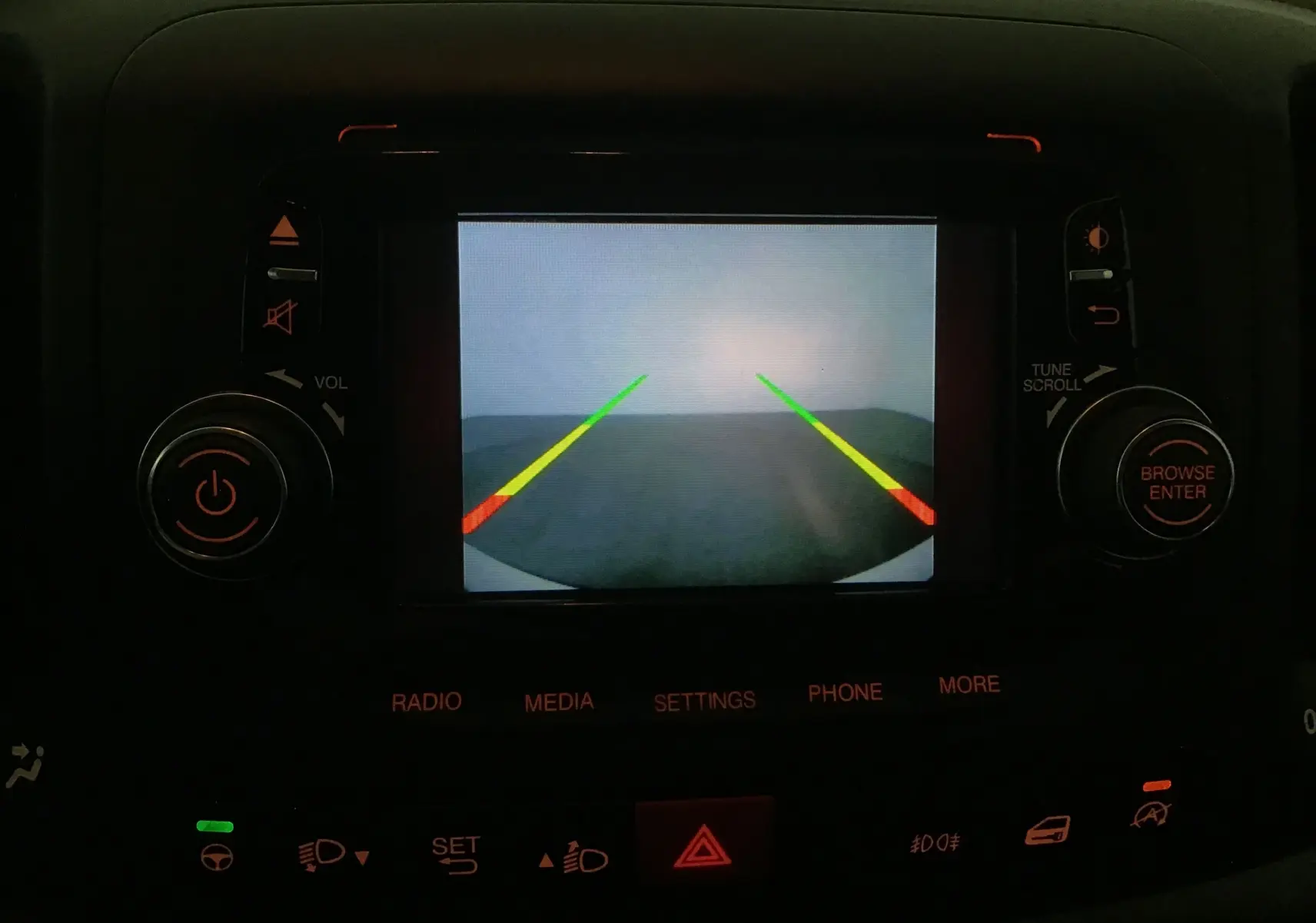 Écran de caméra de recul affichant les lignes de guidage dans l'habitacle sombre d'une Fiat 500L blanche 2015.