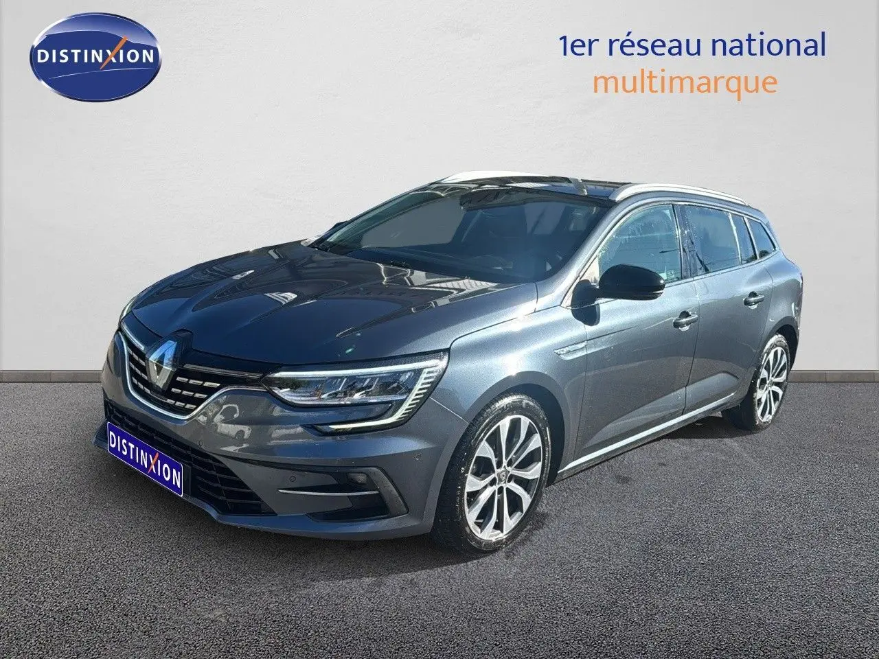 Renault Mégane Break gris titanium métal en 3/4 avant droit, jantes alliage et calandre moderne visible.