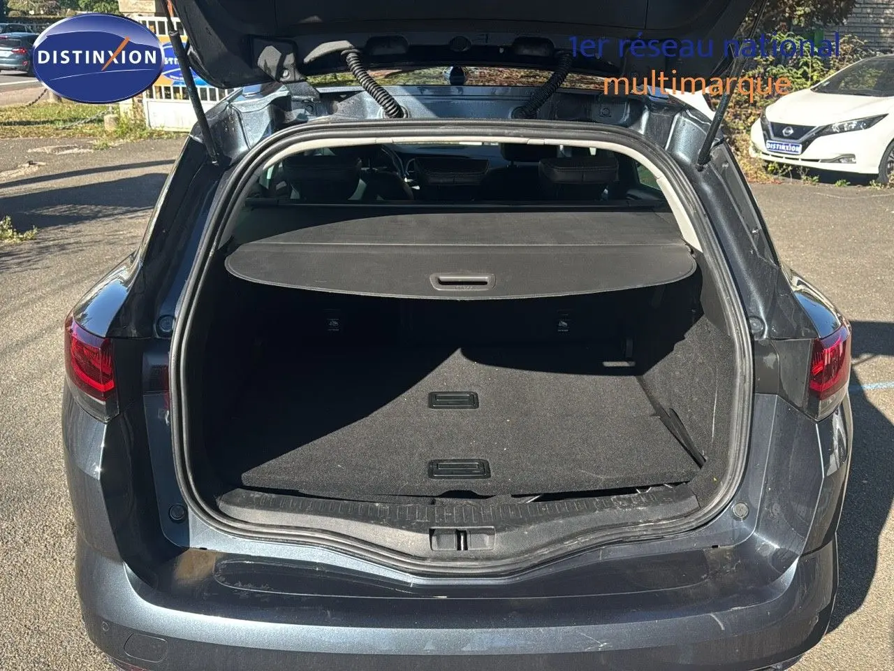 Coffre ouvert vu de l'arrière d'une Renault Mégane Break gris titanium métal, montrant l'espace de chargement vide.