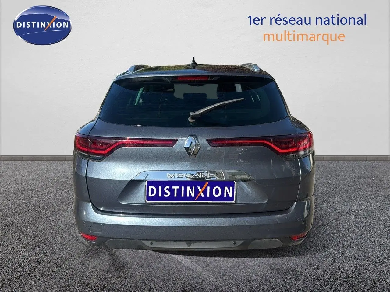 Vue arrière d'une Renault Mégane Break gris titanium métal, avec feux LED et logo distinctif au centre.