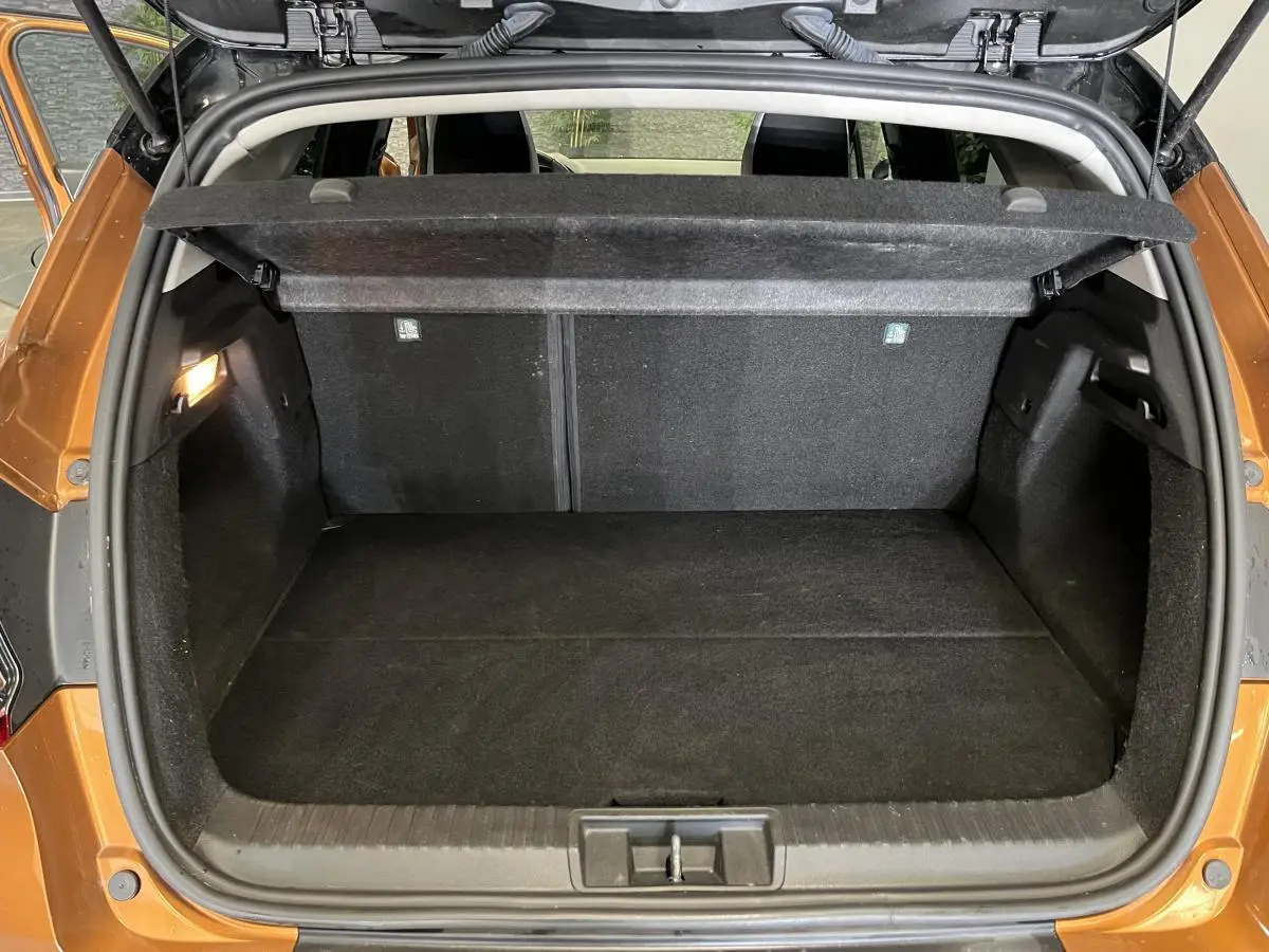Coffre ouvert vu de l'arrière d'un Renault Captur orange 2022 avec cache-bagages et intérieur noir.