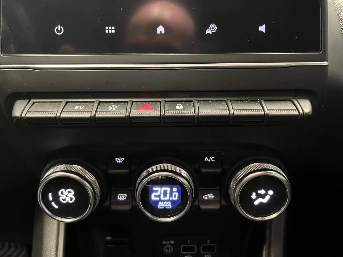 Gros plan sur la console centrale noire du Renault Captur 1.6 E-Tech Hybride avec commandes climatisation et boutons fonctionnels.