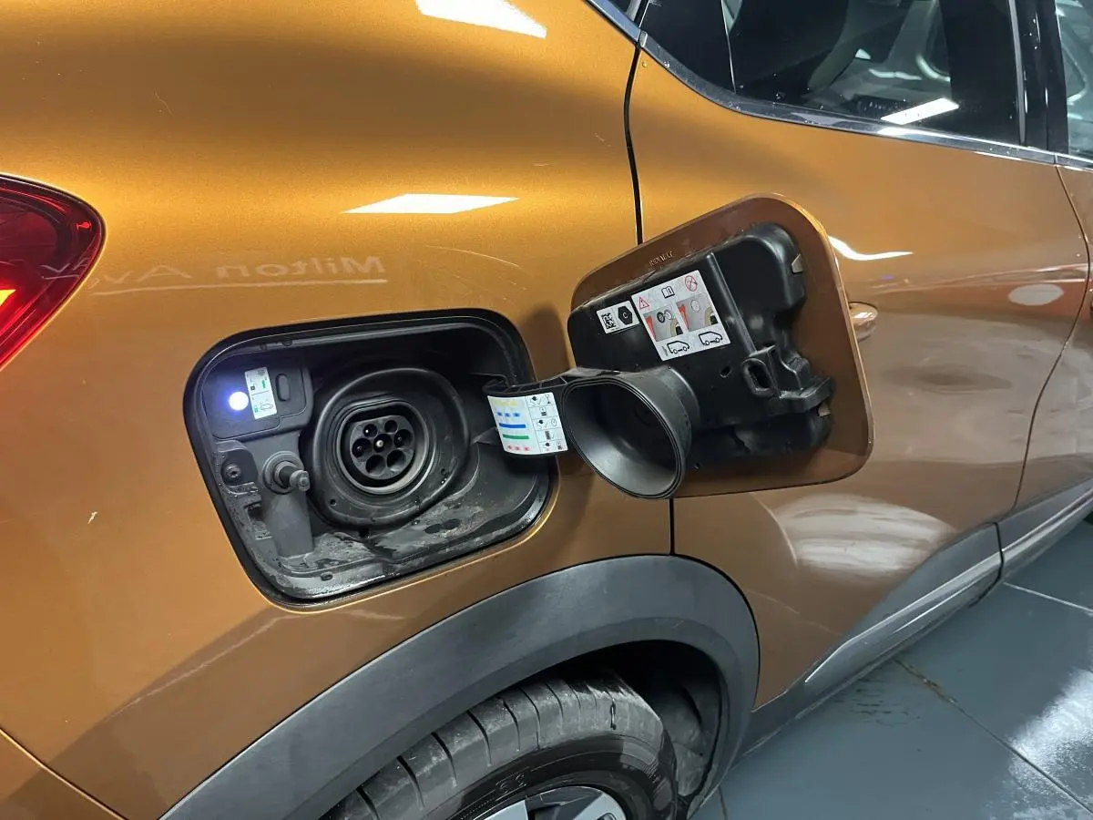 Prise de recharge ouverte côté gauche d’un Renault Captur orange 2022 hybride rechargeable avec peinture bi-ton.