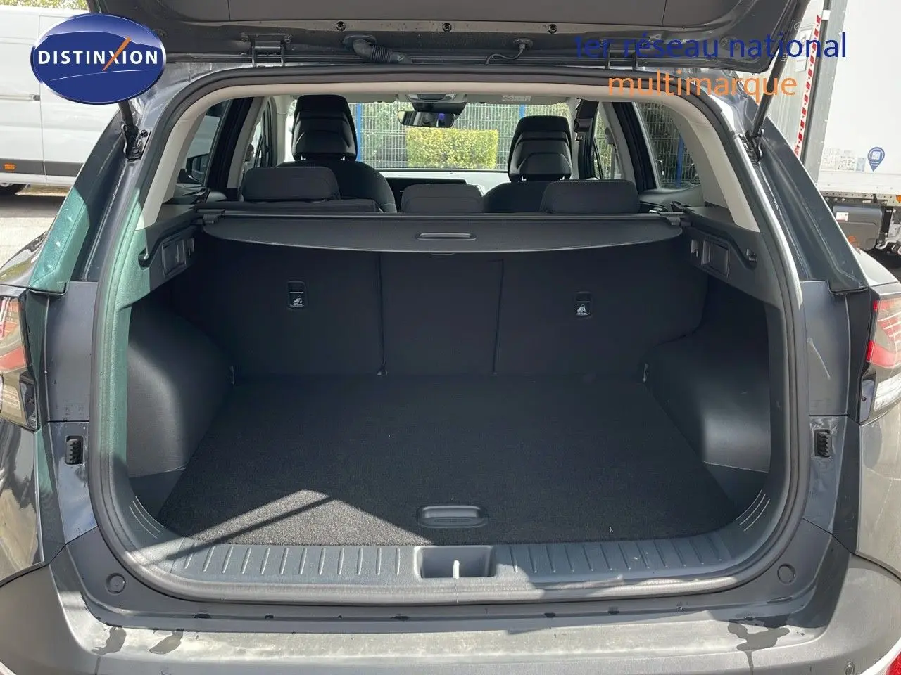 Coffre ouvert d'un Kia Sportage gris foncé 2025, vue arrière montrant l'espace de chargement et les sièges arrière.