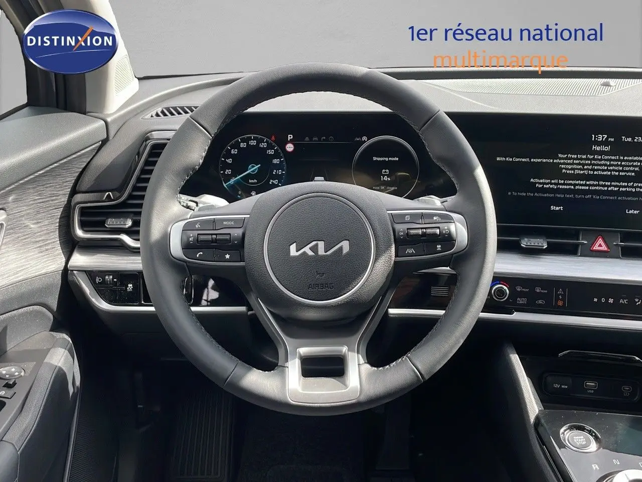 Vue intérieure centrée sur le volant cuir du Kia Sportage gris foncé 2025 avec tableau de bord digital et écran tactile.