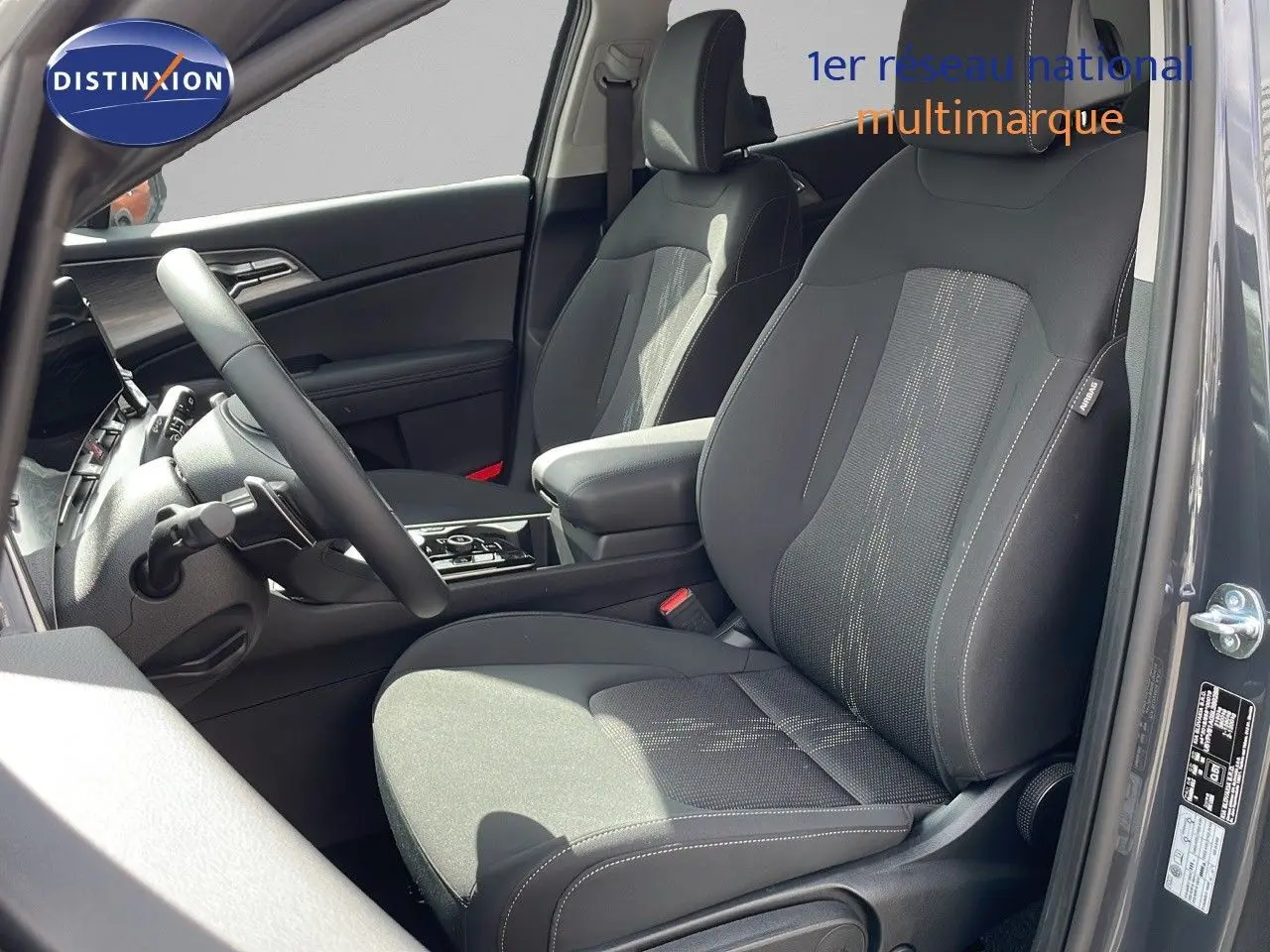 Intérieur du KIA SPORTAGE 2025 gris foncé, vue côté gauche sur les sièges avant en tissu noir avec console centrale.