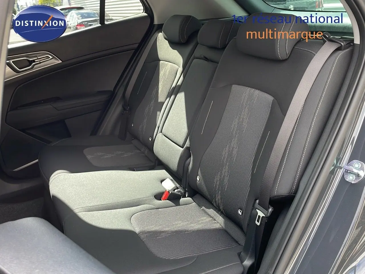 Vue intérieure côté droit des sièges arrière en tissu noir du Kia Sportage gris foncé 2025, avec ceinture de sécurité visible.