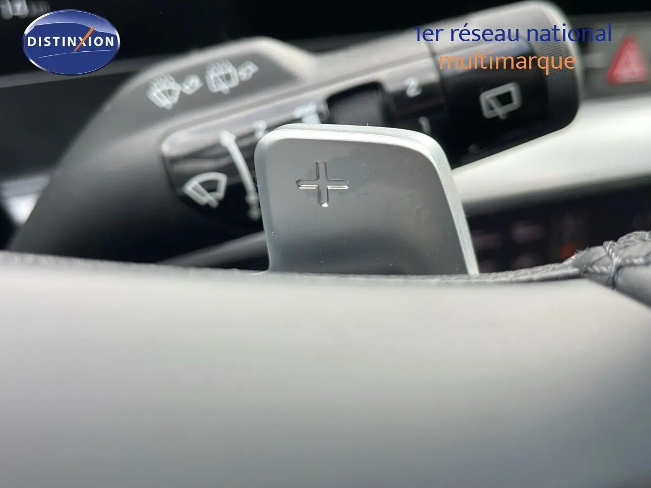 Gros plan sur la palette de changement de vitesse "+" du volant du KIA Sportage gris foncé 2025, intérieur moderne.