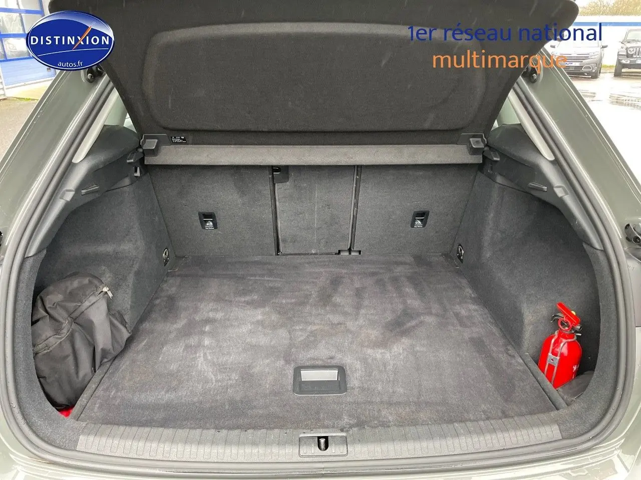 Coffre ouvert d'un Audi Q3 gris Chronos Metal, montrant un espace de chargement propre avec un extincteur rouge à droite.