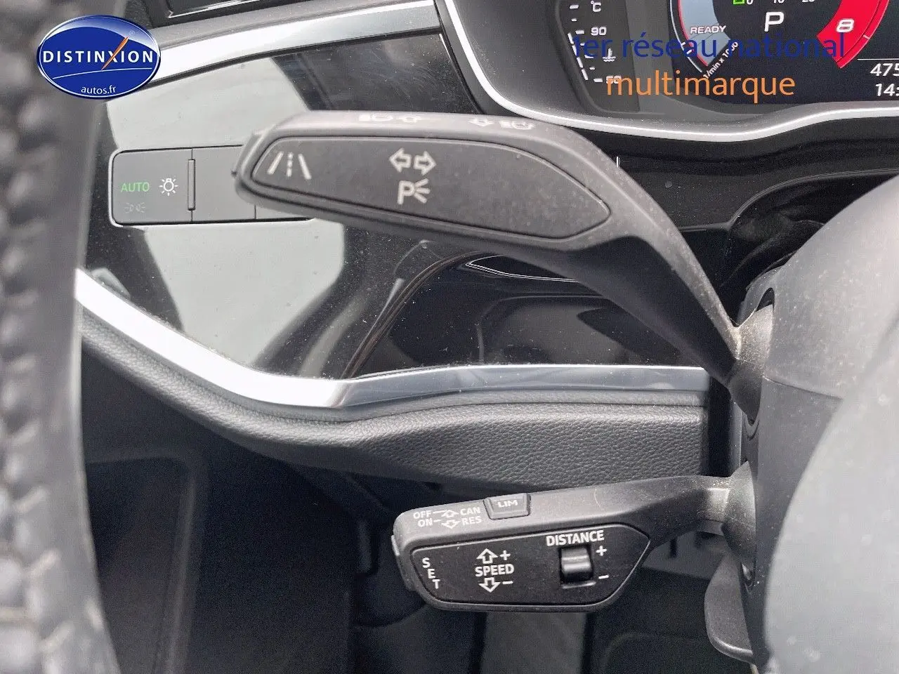 Gros plan sur les commandes au volant de l'Audi Q3 35 TFSI 2019, mettant en valeur les fonctions de régulateur et feux.