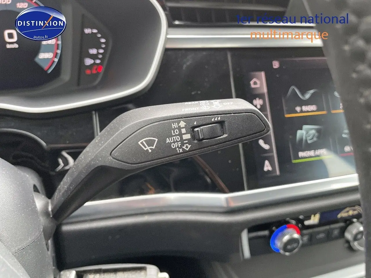 Gros plan sur la commande d’essuie-glace du tableau de bord d’un Audi Q3 35 TFSI gris, avec écran tactile en arrière-plan.