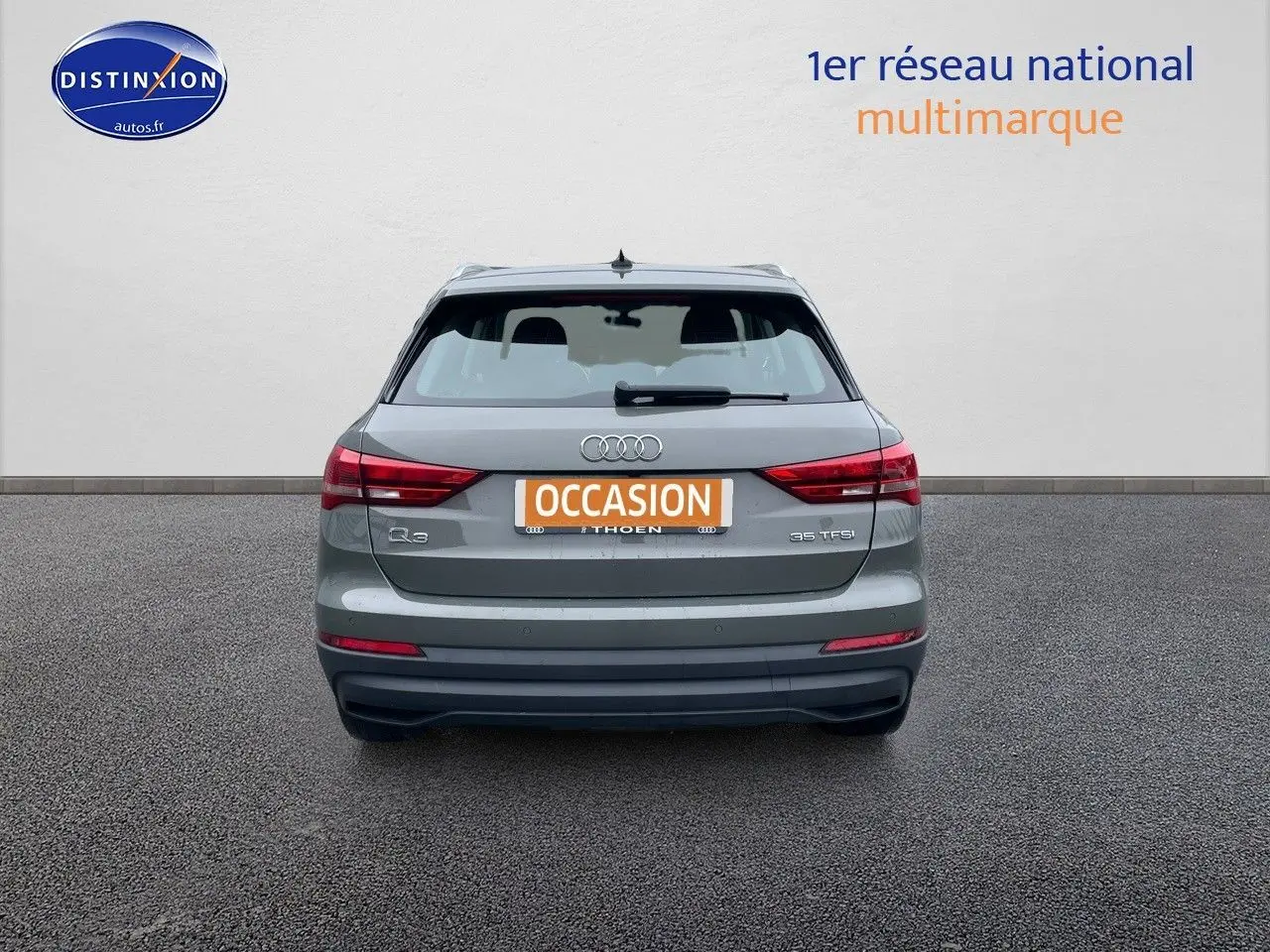 Vue arrière d'un Audi Q3 gris Chronos métal de 2019 avec plaques d'occasion et feux arrière allumés.