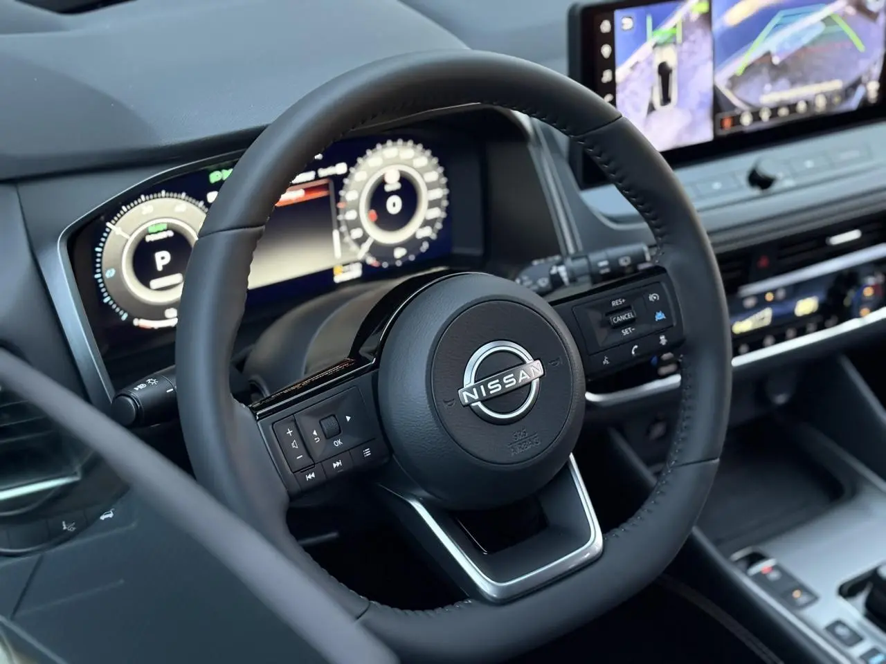Vue rapprochée du volant cuir noir du Nissan Qashqai 2025 avec tableau de bord numérique et écran tactile.