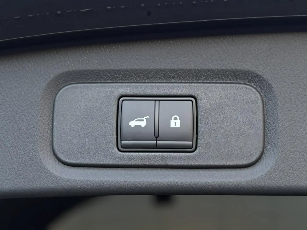 Gros plan sur les boutons d'ouverture électrique du hayon et de verrouillage dans un Nissan Qashqai gris Ceramic.