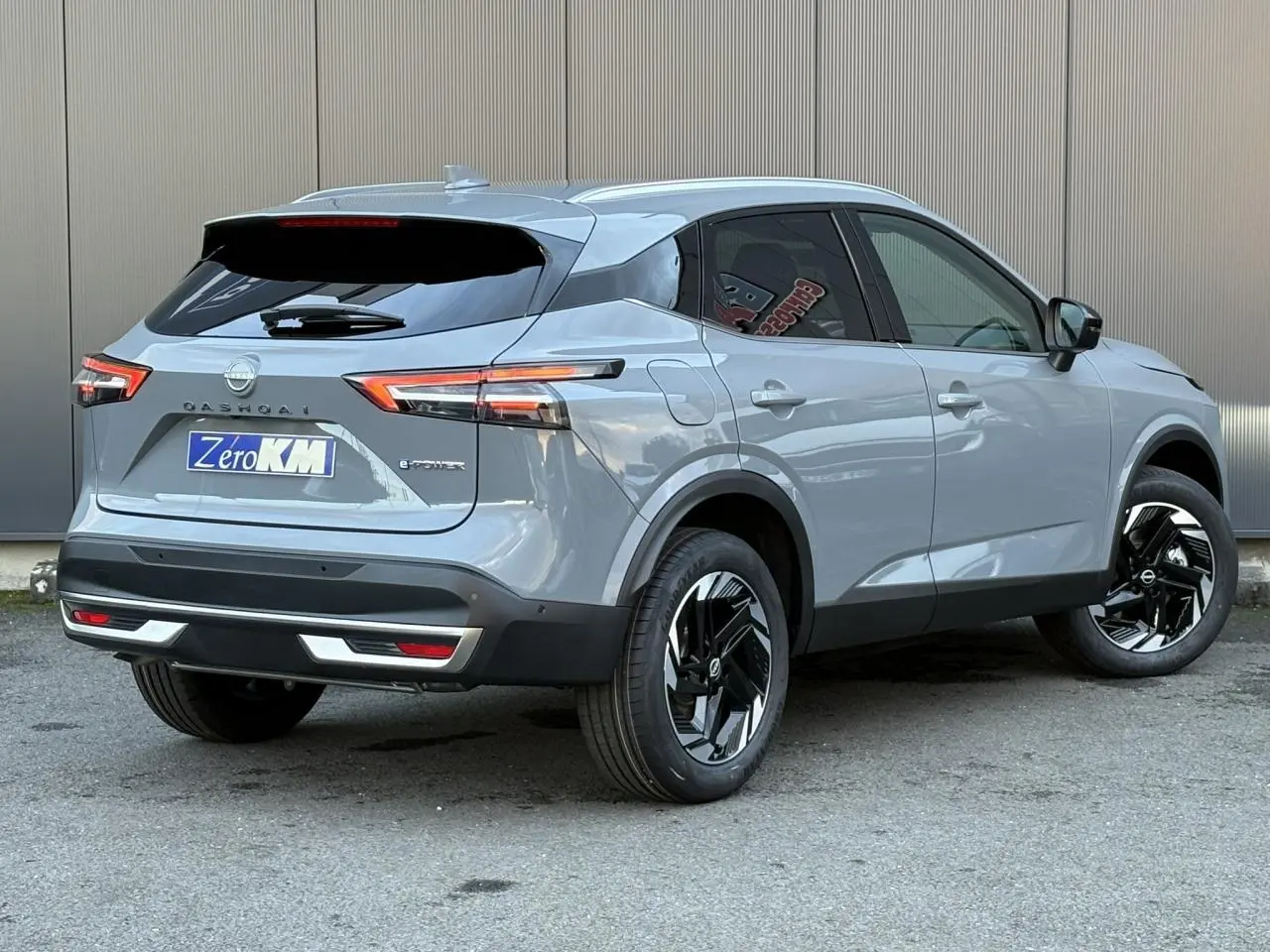 Vue 3/4 arrière droite d'un Nissan Qashqai gris Ceramic avec jantes alliage noires et vitres teintées.