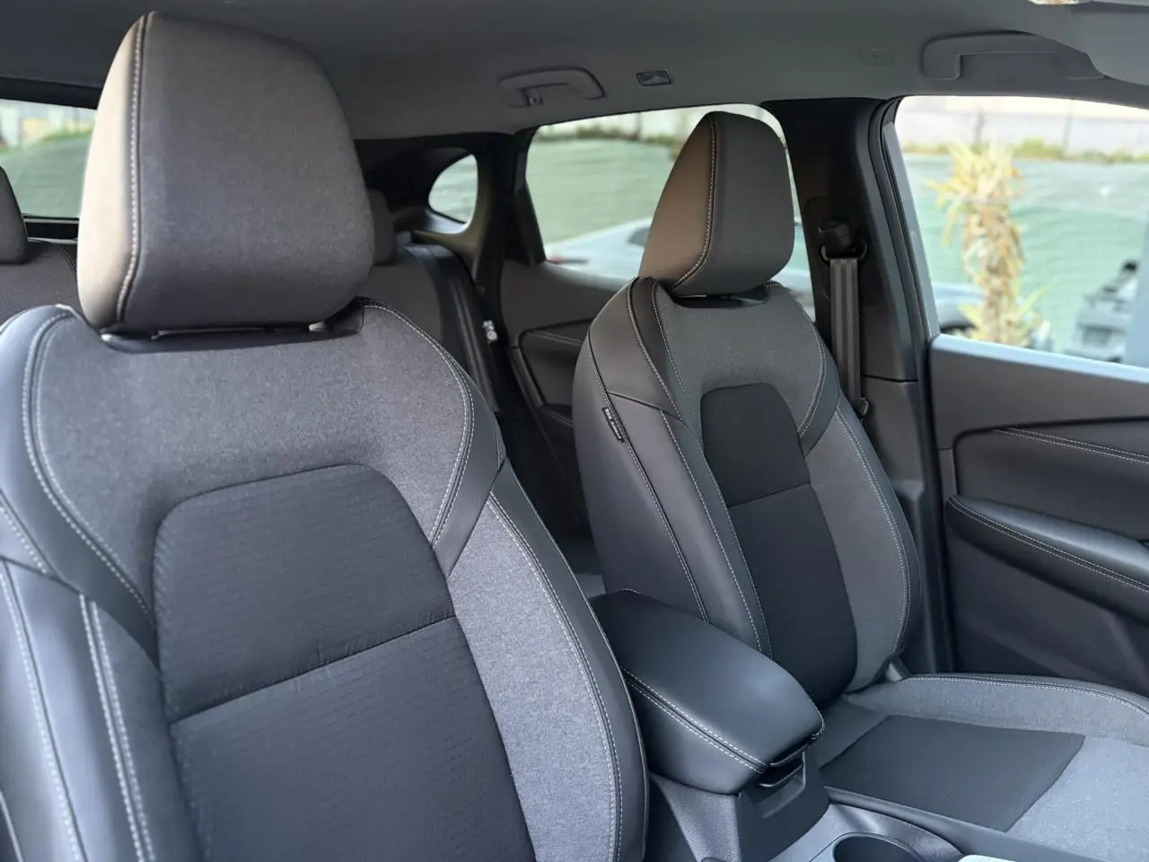 Vue intérieure montrant les sièges avant gris et noirs du Nissan Qashqai III e-Power avec accoudoir central.