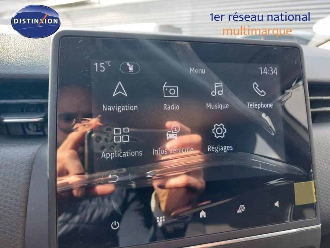 Écran tactile central de la Renault Clio V blanche, affichant le menu principal avec navigation et radio.