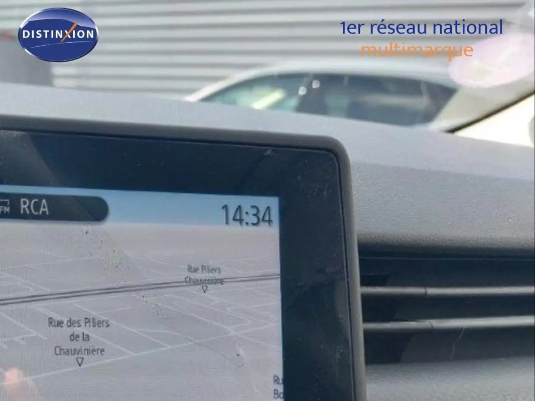 Vue intérieure du tableau de bord de la Renault Clio blanche 2021, avec écran de navigation et aérateurs visibles.