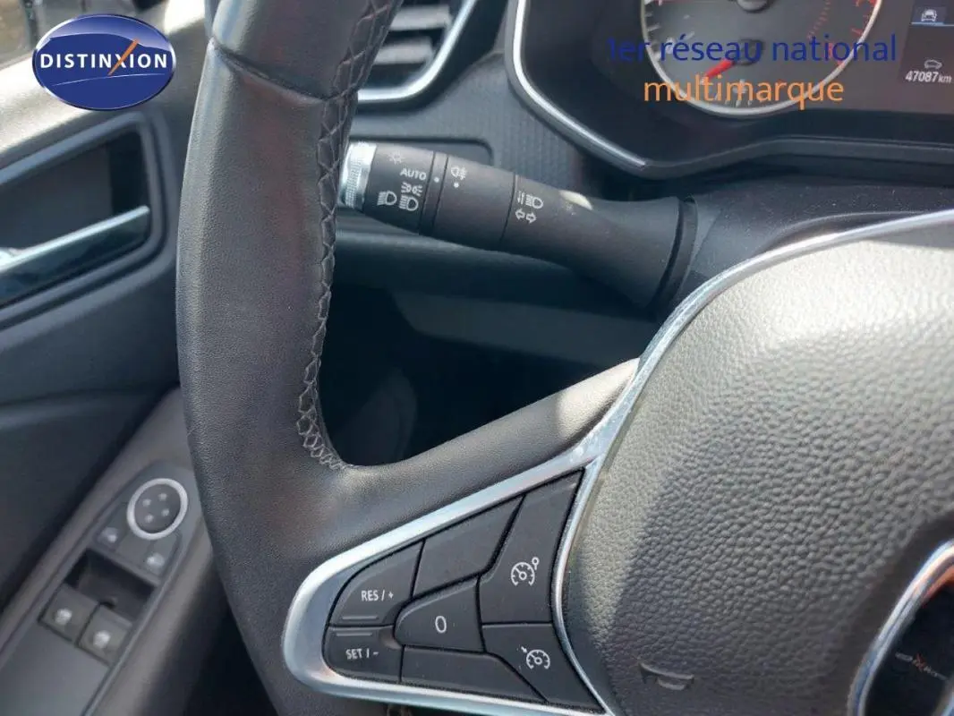 Gros plan sur le volant côté gauche de la Renault Clio blanche 2021, avec commandes du régulateur de vitesse visibles.