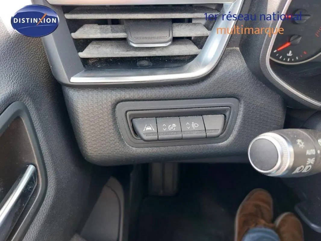 Détail du tableau de bord côté gauche de la Renault Clio blanche, montrant les commandes d'aide à la conduite.