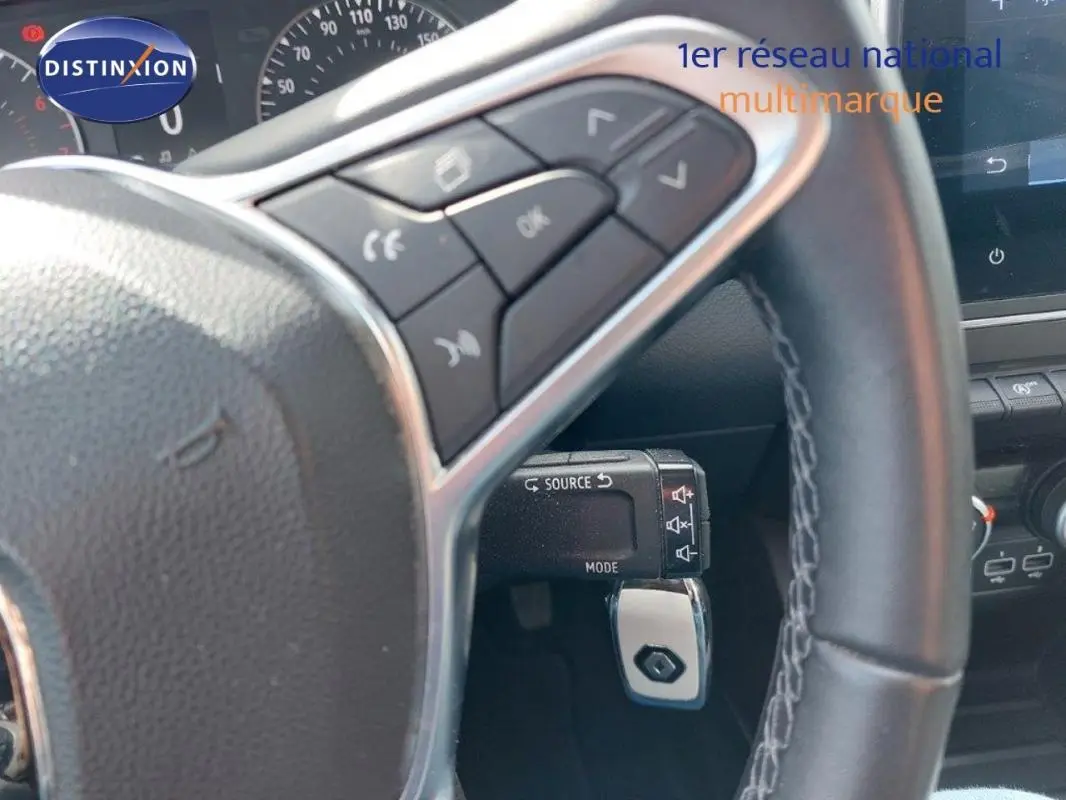 Vue rapprochée du volant de la Renault Clio blanche 2021, avec commandes audio intégrées et tableau de bord partiel.