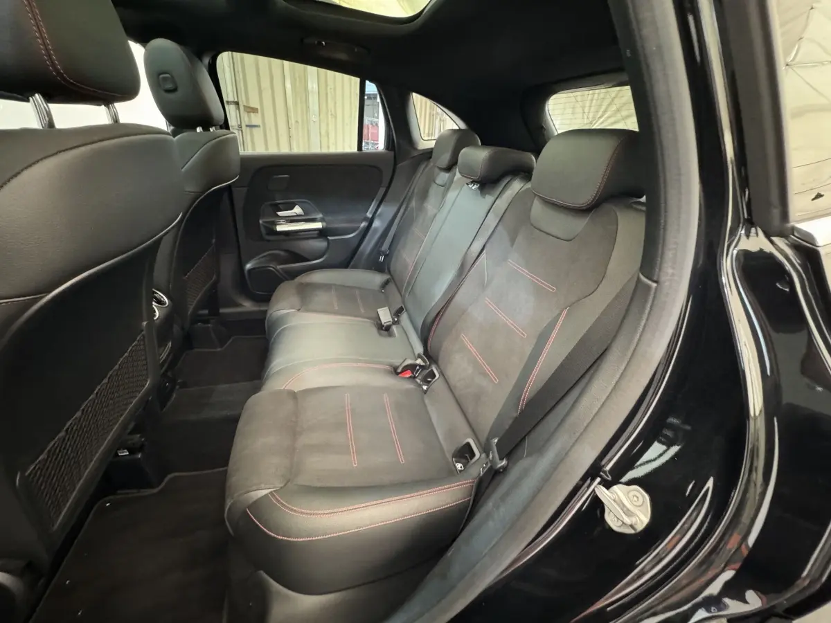 Vue intérieure côté droit des sièges arrière noirs avec surpiqûres rouges d’un Mercedes GLA 250 e AMG Line 2021.