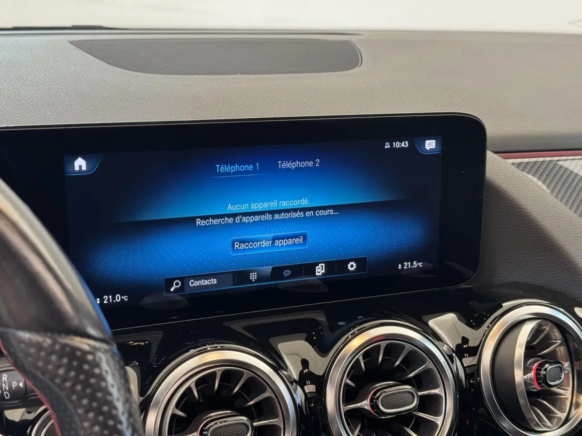 Vue intérieure du tableau de bord noir du Mercedes GLA 250 e AMG Line 2021, avec écran tactile central et aérateurs ronds chromés.