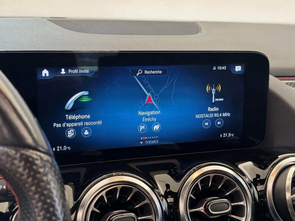 Vue rapprochée de l’écran tactile central et des aérateurs ronds chromés du tableau de bord du Mercedes GLA noir.