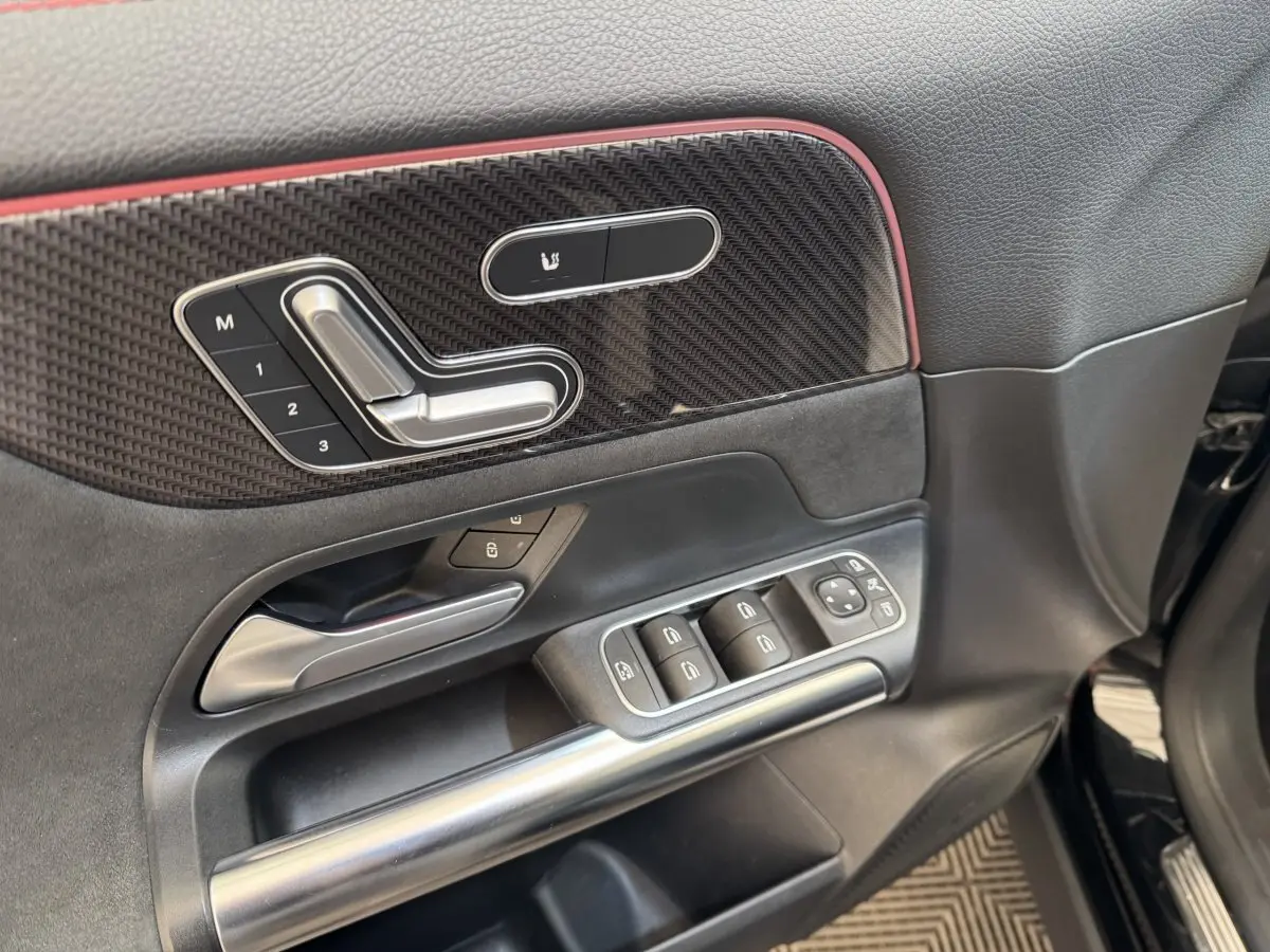Détail de la porte côté conducteur d’un Mercedes GLA 250 e AMG Line noir avec commandes sièges et vitres.
