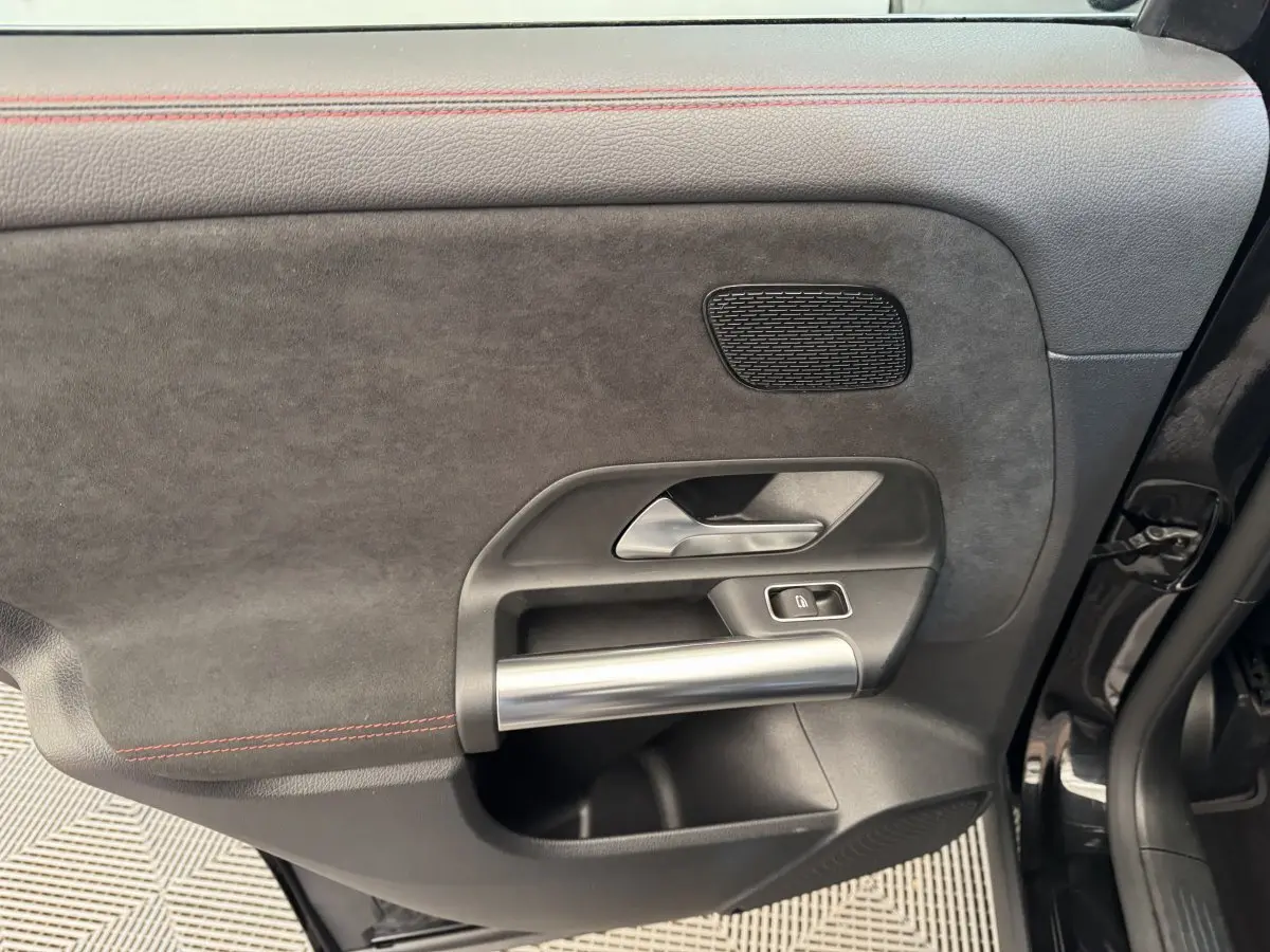 Détail de la porte avant droite noire du Mercedes GLA 250 e AMG Line 2021 avec poignée alu et surpiqûres rouges.