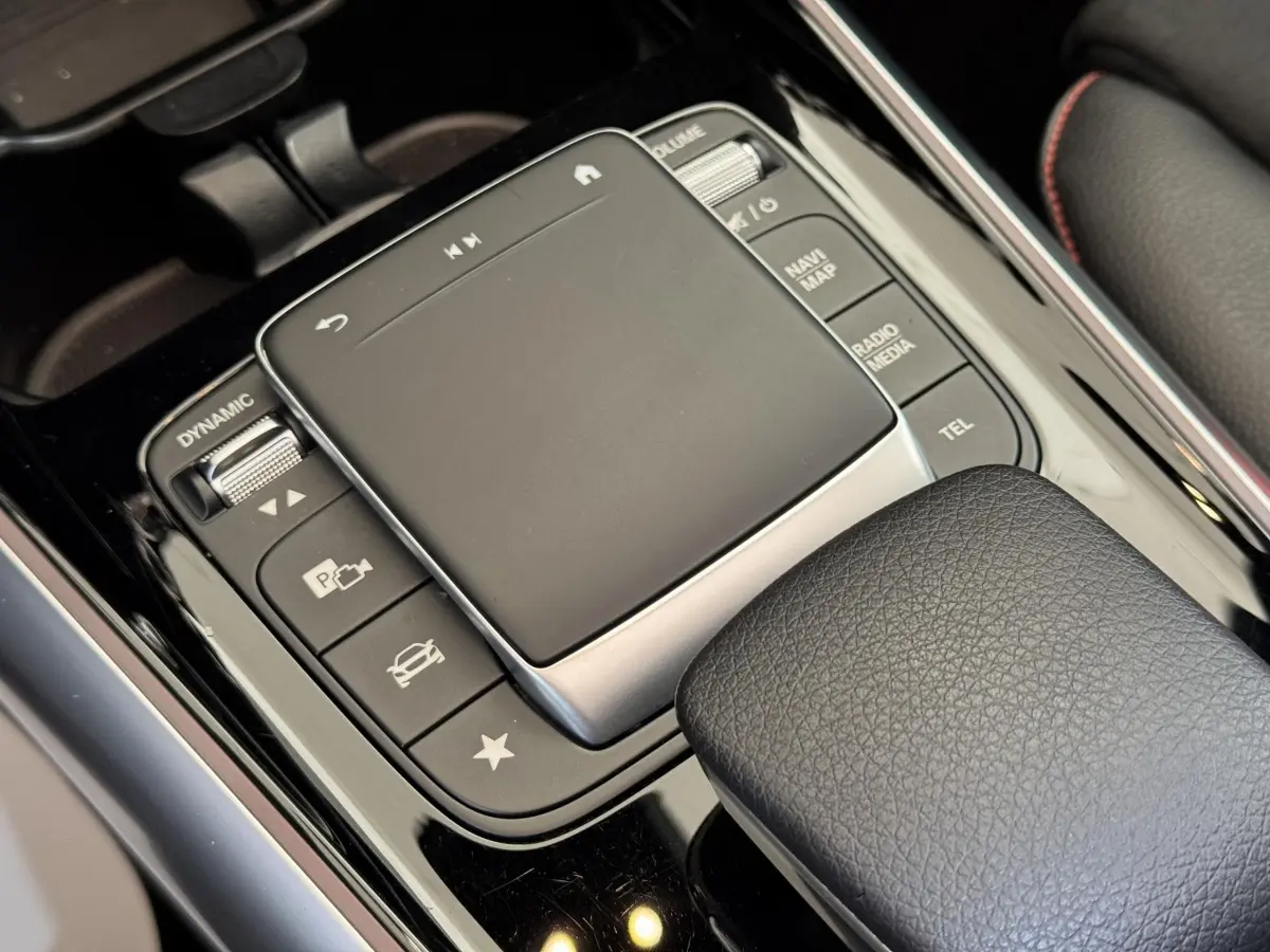 Gros plan sur le pavé tactile central et commandes noires du Mercedes GLA 250 e AMG Line, intérieur cuir noir.