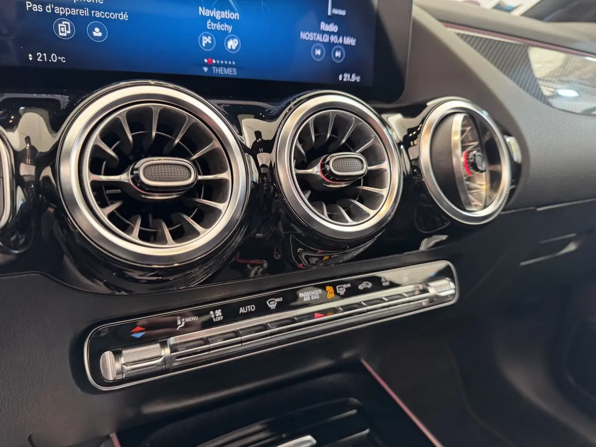 Détail intérieur du tableau de bord noir du Mercedes GLA 250 e AMG Line 2021, avec aérateurs ronds et écran tactile.