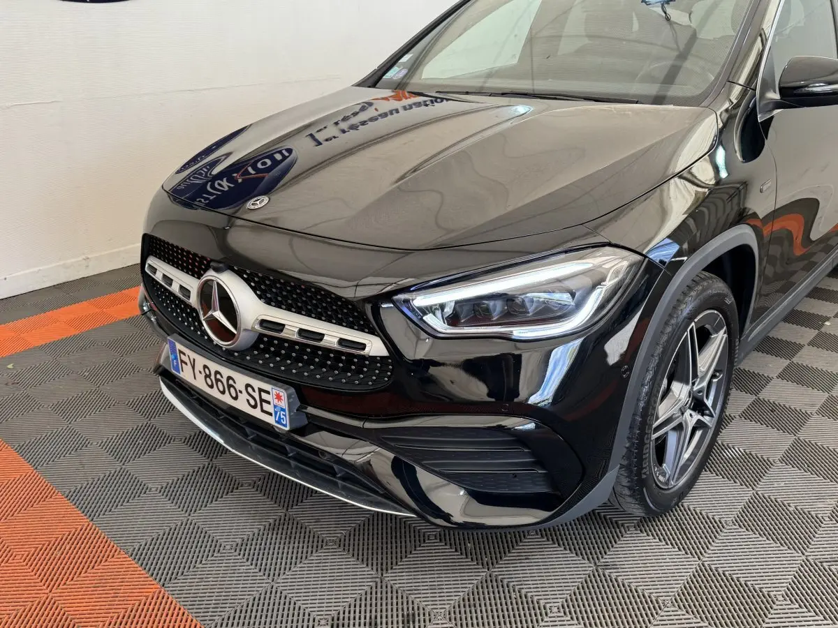 Vue 3/4 avant droit d'une Mercedes GLA 250 e AMG Line noire, avec calandre étoile et phares LED distinctifs.