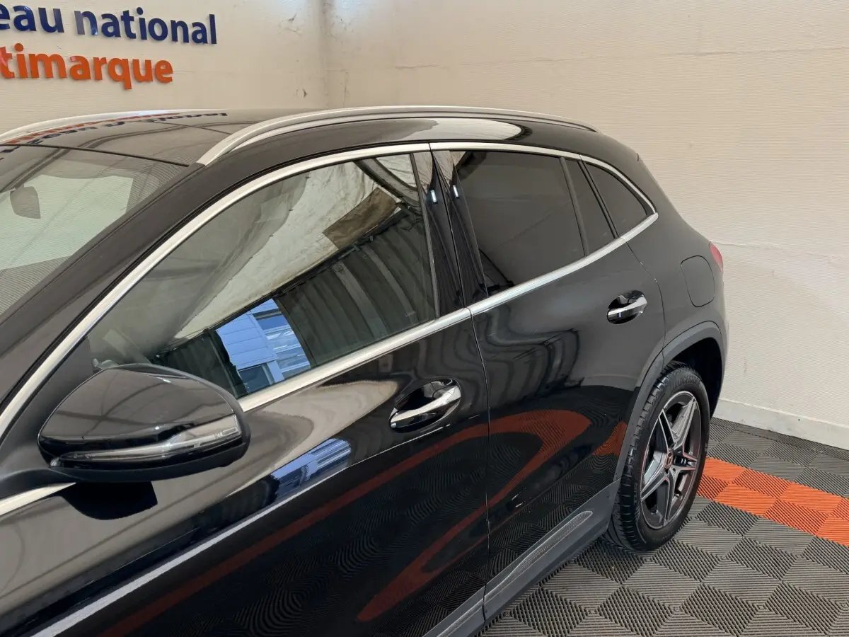 Vue latérale gauche d'un Mercedes GLA 250 e AMG Line noir brillant avec jantes étoile et rétroviseur électrique.