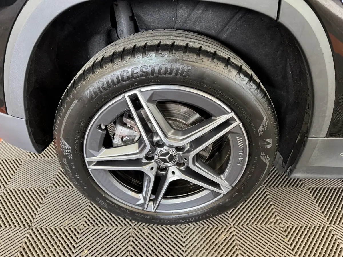 Gros plan sur la roue avant droite noire d'une Mercedes GLA 250 e AMG Line avec jante AMG à cinq branches.