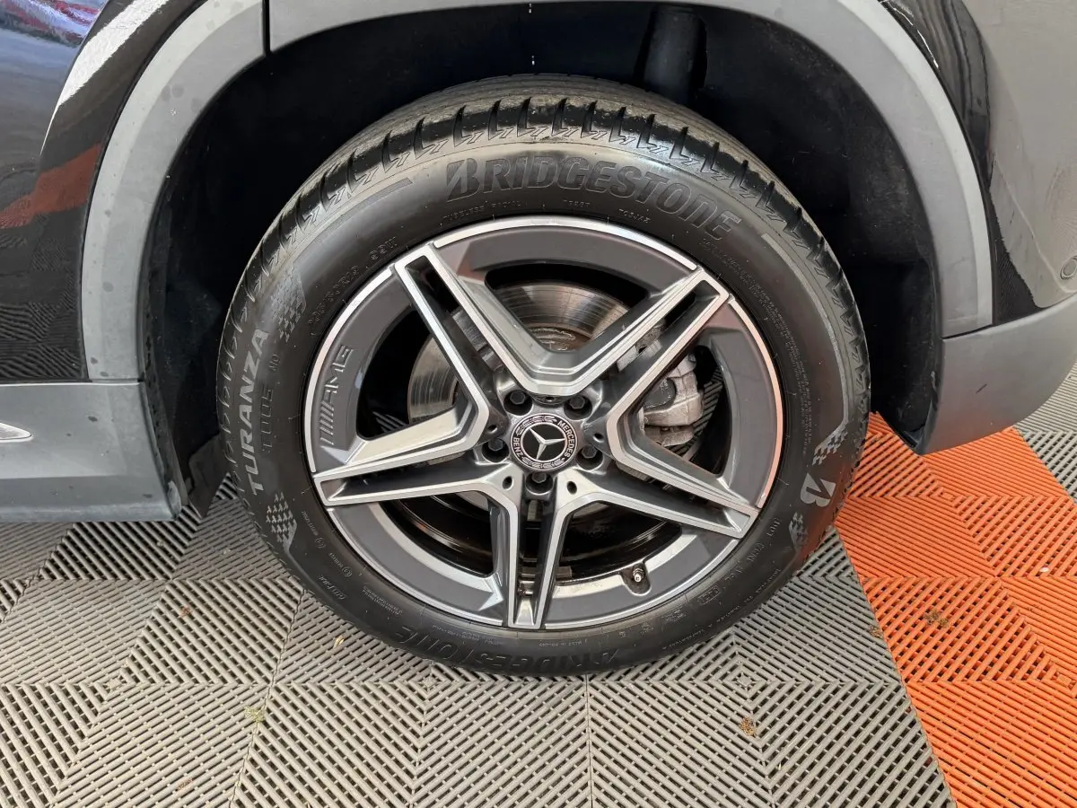 Gros plan sur la roue avant droite noire du Mercedes GLA 250 e AMG Line avec jante AMG à cinq branches.