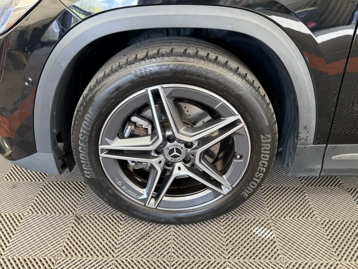 Gros plan sur la roue avant droite noire d’un Mercedes GLA 250 e AMG Line avec jante alliage cinq branches.