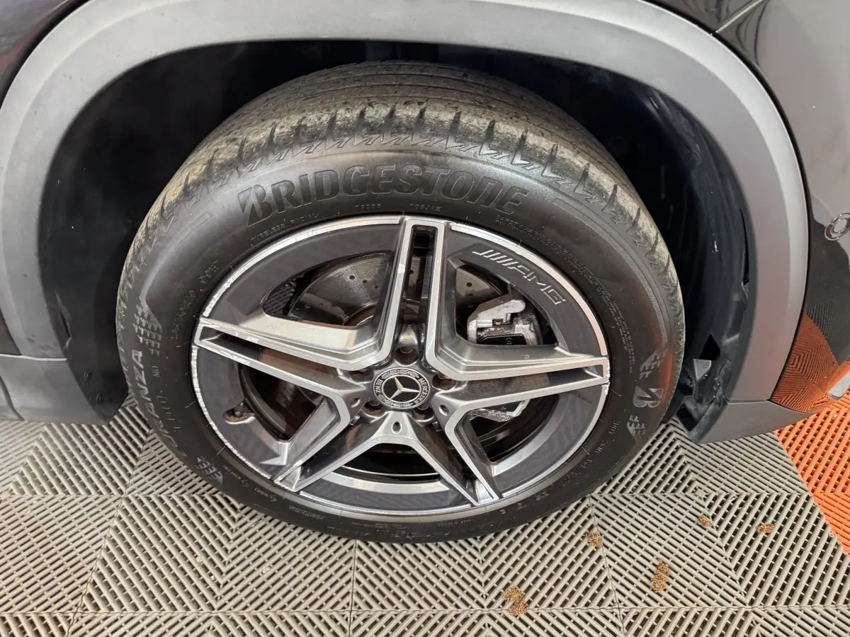 Gros plan sur la roue avant droite noire du Mercedes GLA 250 e AMG Line avec jante AMG cinq branches.