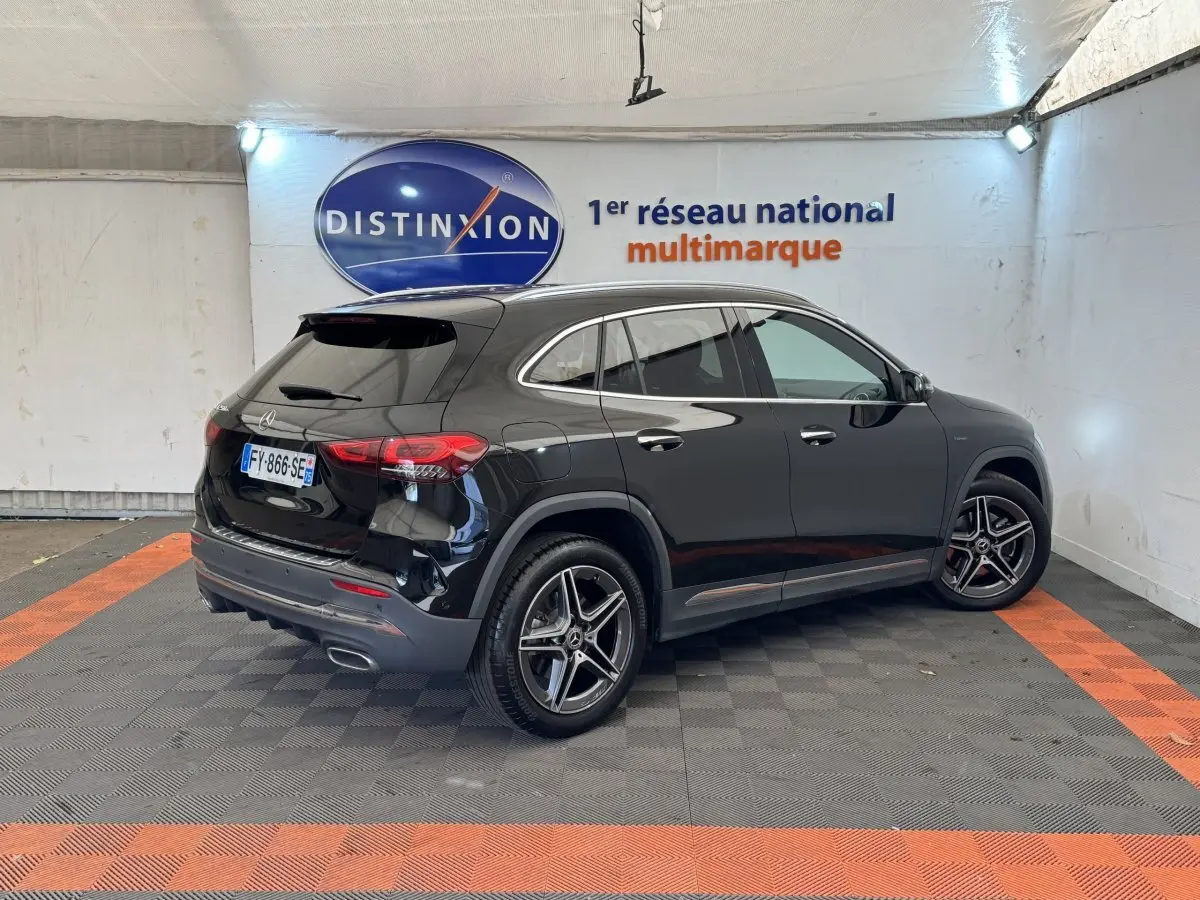 Vue 3/4 arrière droite d'un Mercedes GLA 250 e AMG Line noir brillant, avec jantes alliage et feux LED distinctifs.