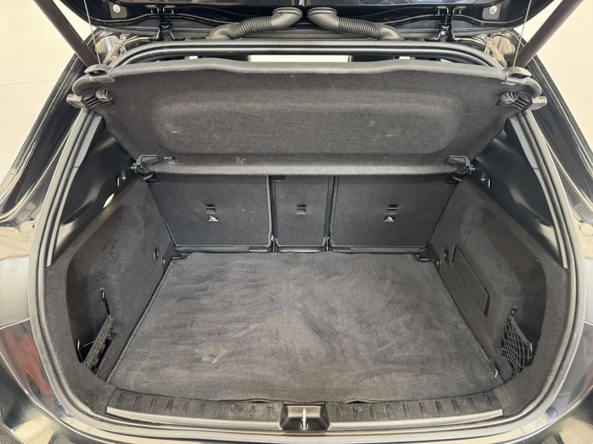Coffre ouvert vu de l'arrière d'un Mercedes GLA 250 e AMG Line noir, montrant un espace de chargement propre et spacieux.