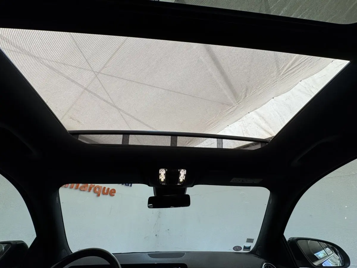 Vue intérieure du toit ouvrant panoramique du Mercedes GLA 250 e AMG Line noir, avec éclairage intérieur allumé.