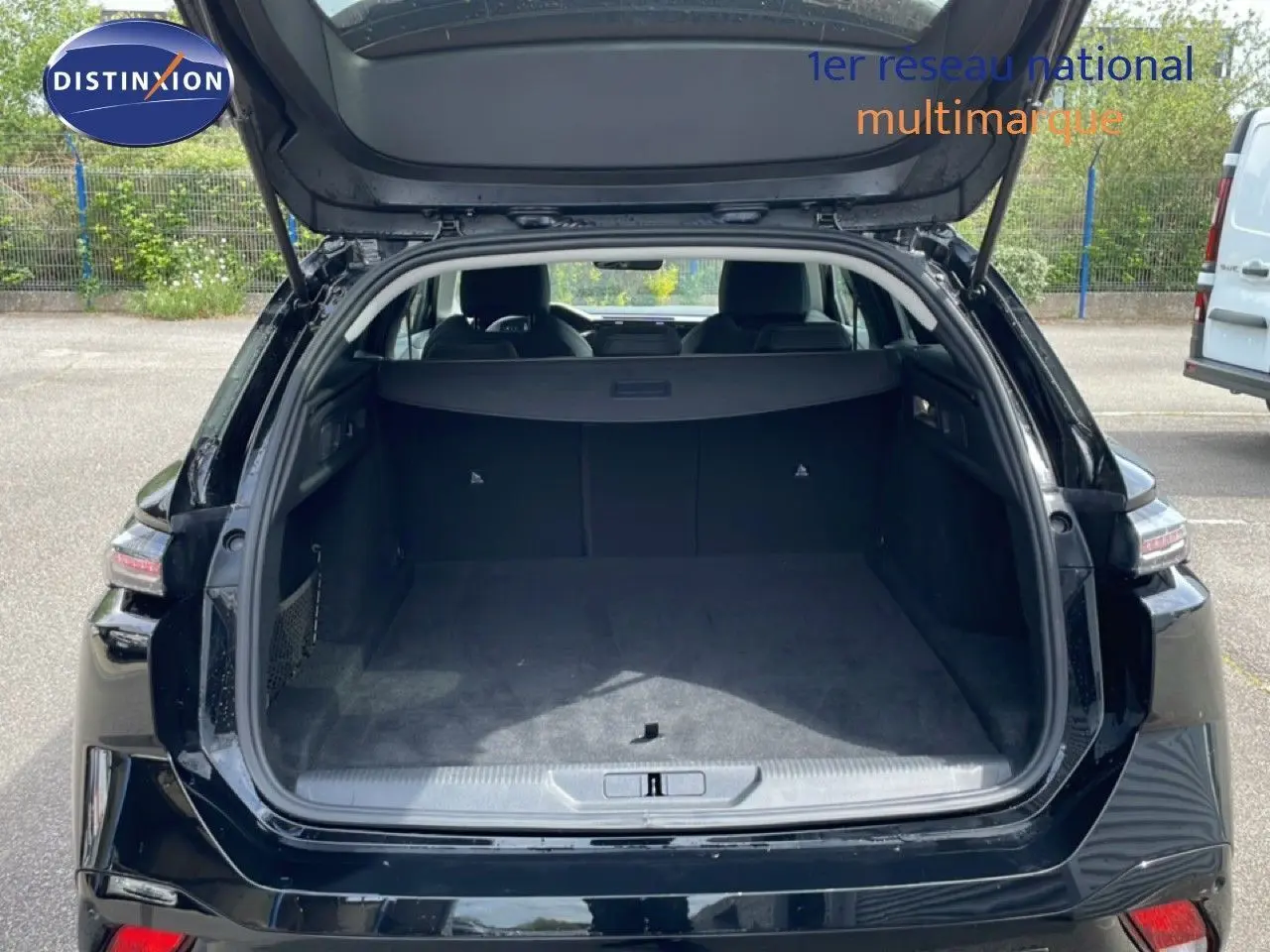 Coffre ouvert vu de l'arrière d'une Peugeot 308 SW noir métal, montrant un espace de chargement spacieux et propre.