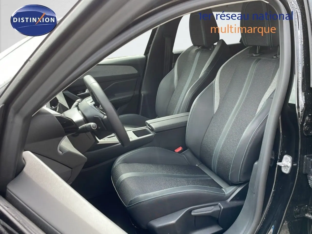 Vue intérieure côté conducteur du Peugeot 308 SW Hybrid 145ch Allure 2025 noir métal, sièges tissu et cuir gris noir.